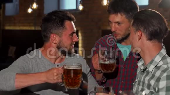 一群朋友对着镜头微笑举着啤酒杯在酒吧里视频的预览图