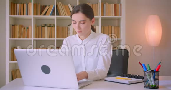 年轻迷人的白人女商人的特写照片她用笔记本电脑看着摄像机脸上洋溢着愉快的笑容视频的预览图