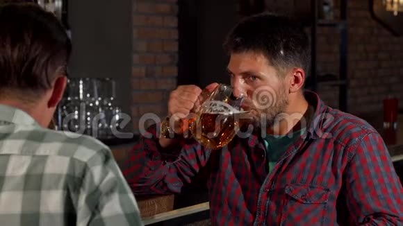 在酒吧喝啤酒时一个长着胡子的成熟男人在和他的朋友聊天视频的预览图