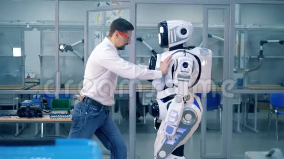一名男性工程师将类似人类的机器人推开然后向他走去视频的预览图