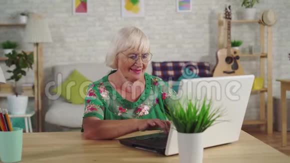 老妇人坐在客厅里用笔记本电脑视频的预览图