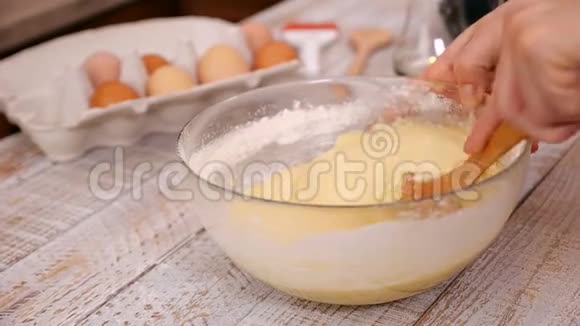 女人用木勺把海绵蛋糕的原料混合在玻璃碗里视频的预览图