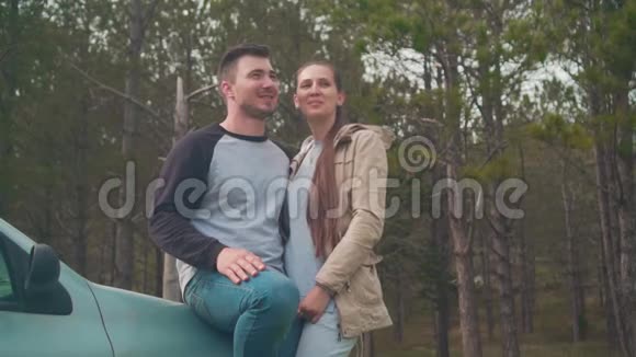 一对夫妇一个男人和一个女孩站在森林里的一辆车上他们在笑那家伙在吻那个女孩视频的预览图