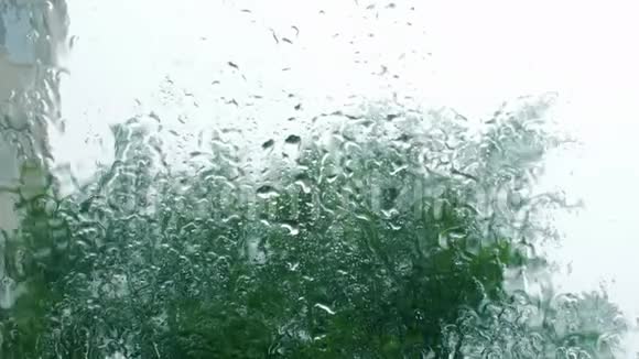 雨滴落在窗户玻璃上建筑物在背景上从窗户看房子暴风雨天气强烈视频的预览图