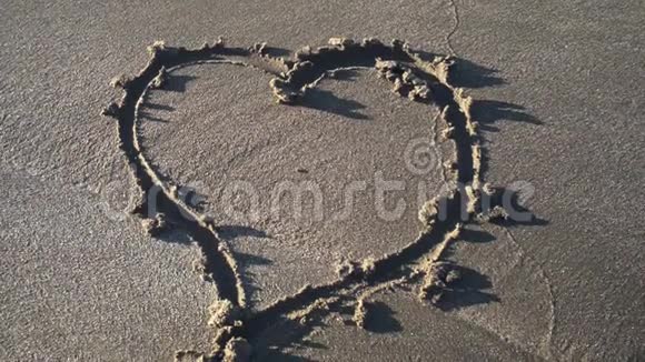 手在沙子上画出的心的符号视频的预览图