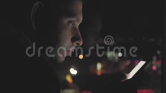 年轻人晚上在模糊的城市灯光面前使用智能手机手机应用技术视频的预览图
