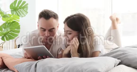 一对夫妇用数码平板电脑躺在床上视频的预览图