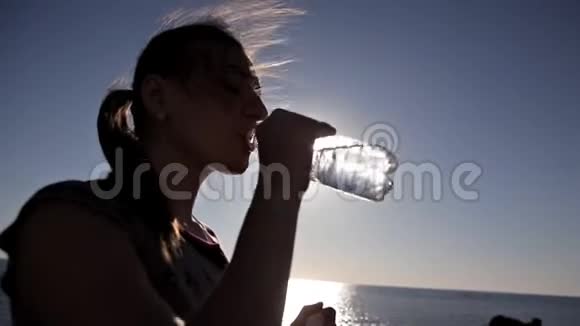 在海边的水瓶里喝酒的女人视频的预览图