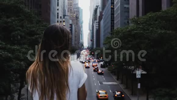 在美国纽约市中心站在桥上看交通道路的年轻时尚女性的后景视频的预览图