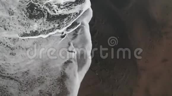 鸟瞰海浪拍打在黑色沙滩上视频的预览图