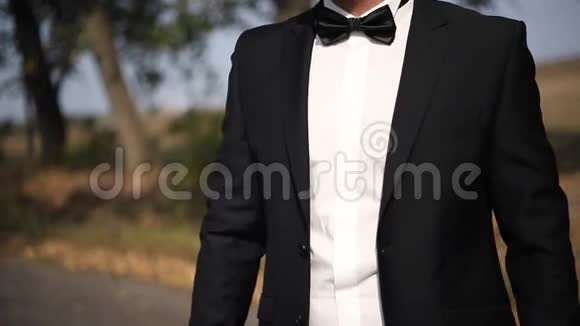 穿着黑色西装领结站在外面的房间树的小巷时装男视频的预览图