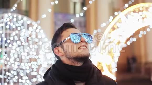 时尚的大胡子男人在庆祝新年城市圣诞树花环和灯光反射在镜子里视频的预览图