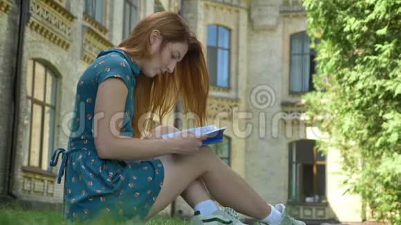 集中年轻姜女学生看书坐在大学大楼附近的公园里外面阳光明媚视频的预览图
