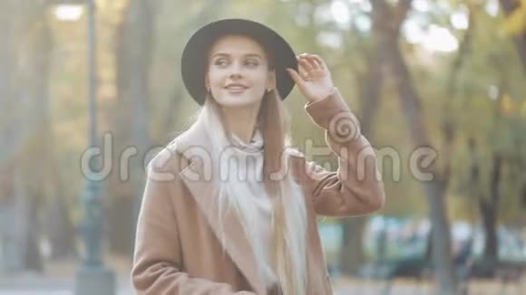 迷人的女孩一副浪漫的样子戴着黑帽子走在公园的小巷里环顾四周露出惊人的微笑视频的预览图