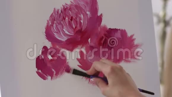 女孩艺术家的特写在白色画布上画粉红色的花视频的预览图