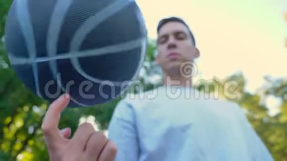 在公园户外球场低角度旋转篮球的年轻人视频的预览图