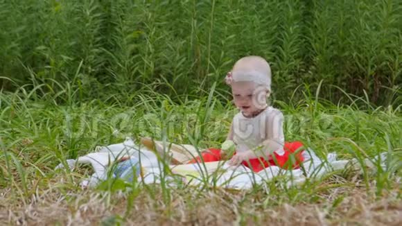 高清童年蹒跚学步的女孩坐在地上玩她的玩具在公园里视频的预览图