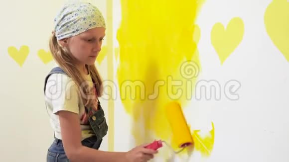 小孩用黄色画白墙视频的预览图