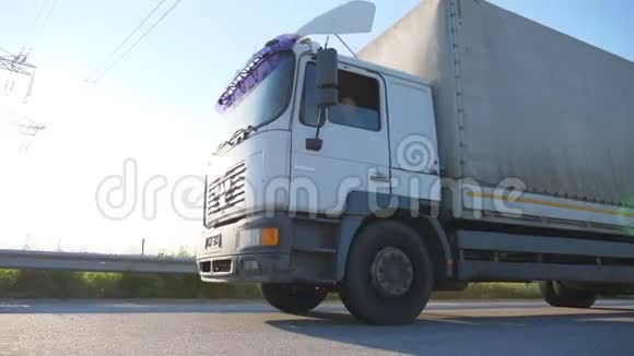 摄像机跟踪到高速公路上的卡车上卡车在乡间飞驰背景是日落底部侧面视图视频的预览图