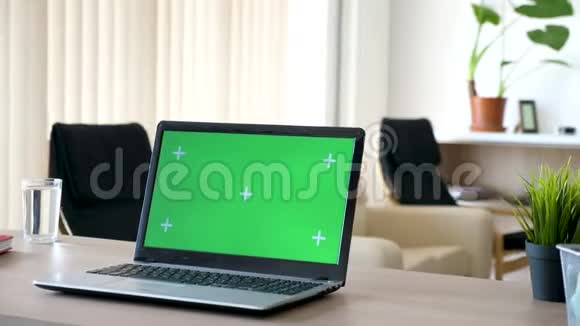 客厅办公桌上的笔记本电脑带有隔离的绿色屏幕和跟踪标记视频的预览图