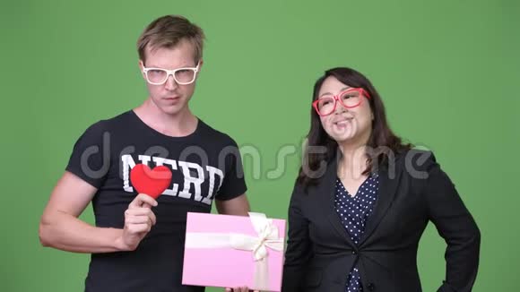 成熟的亚洲女商人和年轻的斯堪的纳维亚书呆子一起庆祝情人节视频的预览图