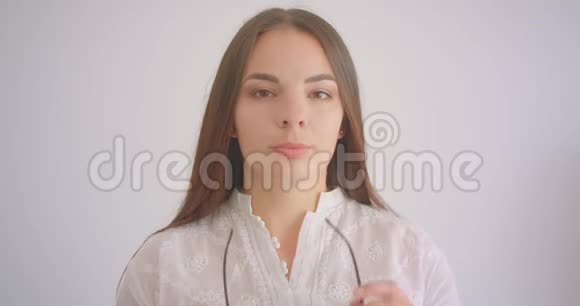 年轻漂亮的白种人女学生戴着眼镜看镜头背景与白色隔离视频的预览图