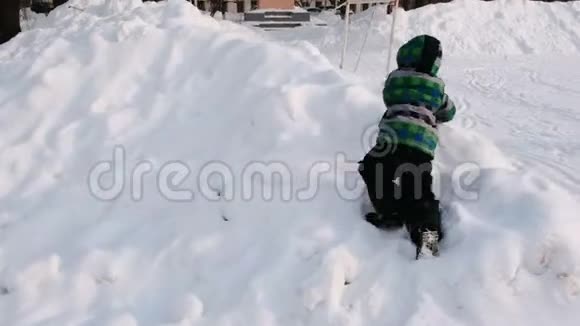 男孩爬雪漂流在冬天的城市公园在雪天与降雪视频的预览图