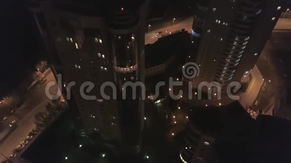 无人机在夜间沿着高楼大厦飞来飞去窗户里亮着灯视频的预览图