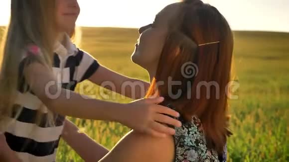 一个金发碧眼的小女孩拥抱着她的母亲微笑着在日落时美丽的麦田景色视频的预览图