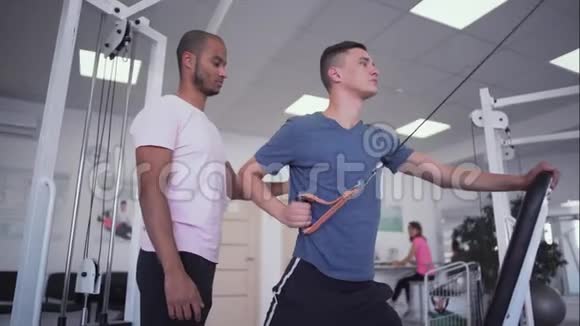 非裔美国人教练帮助年轻人训练健身房里的人视频的预览图