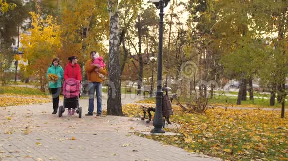 年轻的一家人带着孩子和婴儿车步行去公园慢动作视频的预览图