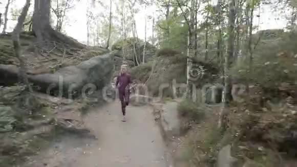 快乐的年轻女子穿过一个岩石和石头之间的旅游通行证稳定摄像机跟踪镜头视频的预览图