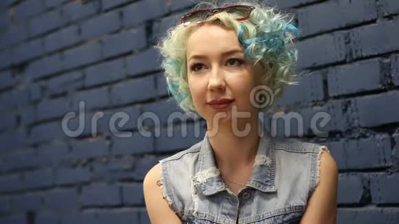 一位年轻貌美的白人女子在砖墙背景下向外眺望的肖像视频的预览图