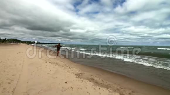 年轻快乐的女人在海滩上奔跑视频的预览图