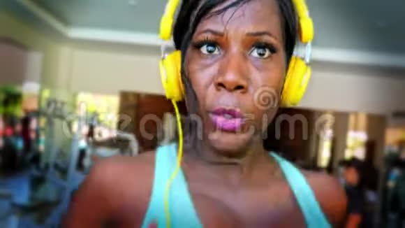 正面近距离拍摄年轻有魅力的适合黑人的美国女人在跑步机上进行硬冲刺视频的预览图