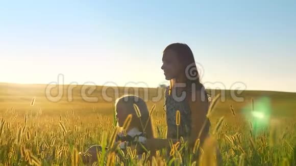 年轻的母亲向女儿展示了一些东西微笑着坐在小麦或黑麦地中间美丽的视频的预览图