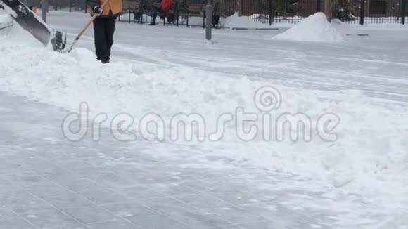 暴风雪过后穿着橙色夹克的工人用铲子和雪犁拖拉机打扫街道市政城市道路养护视频的预览图