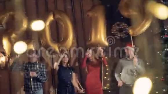 在圣诞树附近跳舞的人拿着金色的气球制作了一个数字20192019新年概念视频的预览图