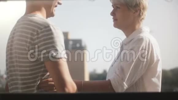 镜头转向快乐的男人和女人赤脚站在美丽的阳光公寓阳台布鲁克林视频的预览图