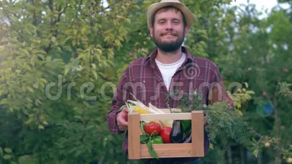 在花园的绿树背景下一位快乐的农夫手里拿着蔬菜篮子视频的预览图
