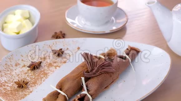 巧克力俄式薄饼布里尼和凝乳馅在盘子里提供了一杯茶和黄油侧视视频的预览图