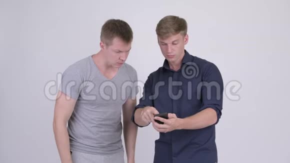 两个年轻英俊的男人用电话看起来很震惊视频的预览图