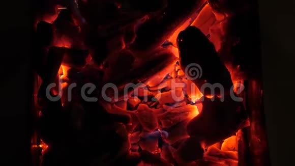 炽热的木炭在黑暗中熊熊燃烧特写镜头晚上红煤在烤架里燃烧慢动作视频的预览图