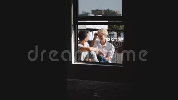 镜头接近美丽的年轻浪漫夫妇坐在一起拥抱和交谈在一个小阳光阳台视频的预览图