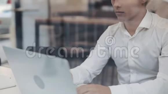 一位严肃的年轻商人坐在一家咖啡馆的桌子旁用笔记本电脑工作自由沟通信息技术成功视频的预览图