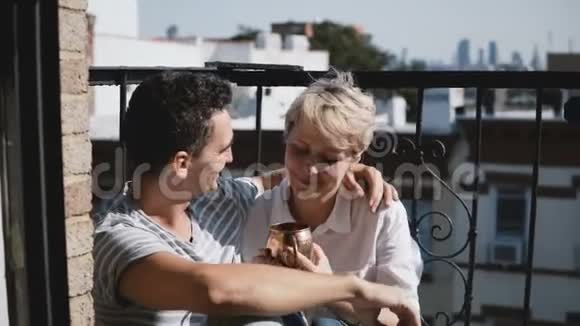 欧洲年轻女性和西班牙男人在阳光明媚的小阳台上喝咖啡带着青铜金属杯子交谈和微笑视频的预览图