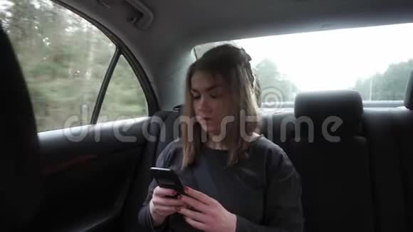 年轻女子坐在汽车后座上注意力集中视频的预览图