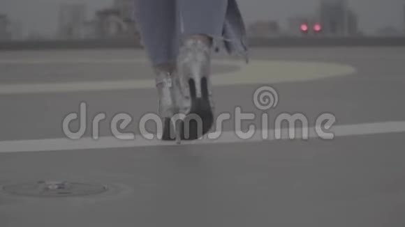一个穿着鞋跟凉鞋的女孩的腿走在城市的景色背景上Slog视频的预览图