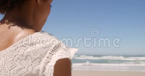 年轻的非裔美国妇女在阳光4k的海滩上放松的后景视频的预览图