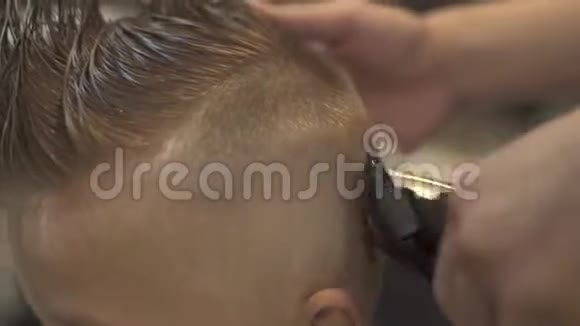 男美发师使用电动剃须刀为儿童发型用发机理发时的肖像小男孩视频的预览图
